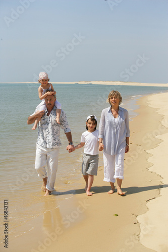 Homme et femme marchant au bord de la mer avec des enfants photo