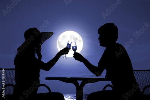 Pair silhouette is held by goblet with wine on a moon night