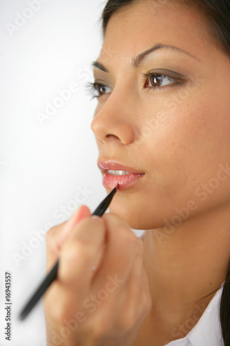 femme se faisant maquiller les lèvres sur fond blanc