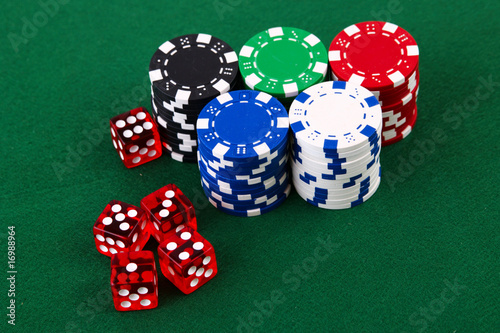 Stacks of casino chips and dice on green