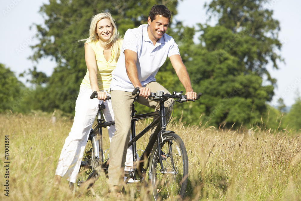 Couple riding tandem in countryside