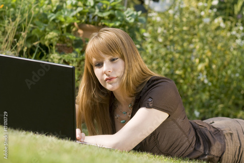 Junge Frau im Garten am Lptop photo