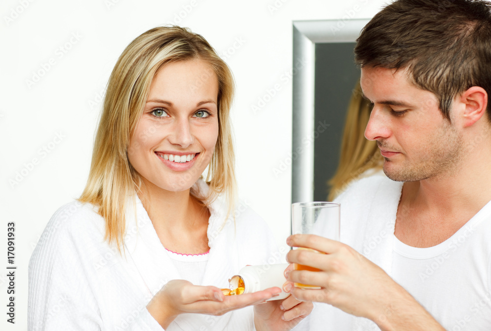 Beautiful woman holding pills and man drinking orange juice Beautiful woman holding pills and man drinking orange juice