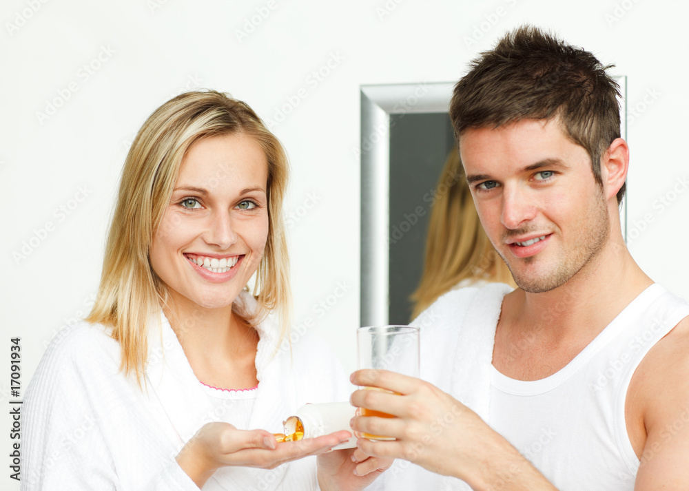 Woman holding pills and man with a glass of orange juice Woman holding pills and man with a glass of orange juice