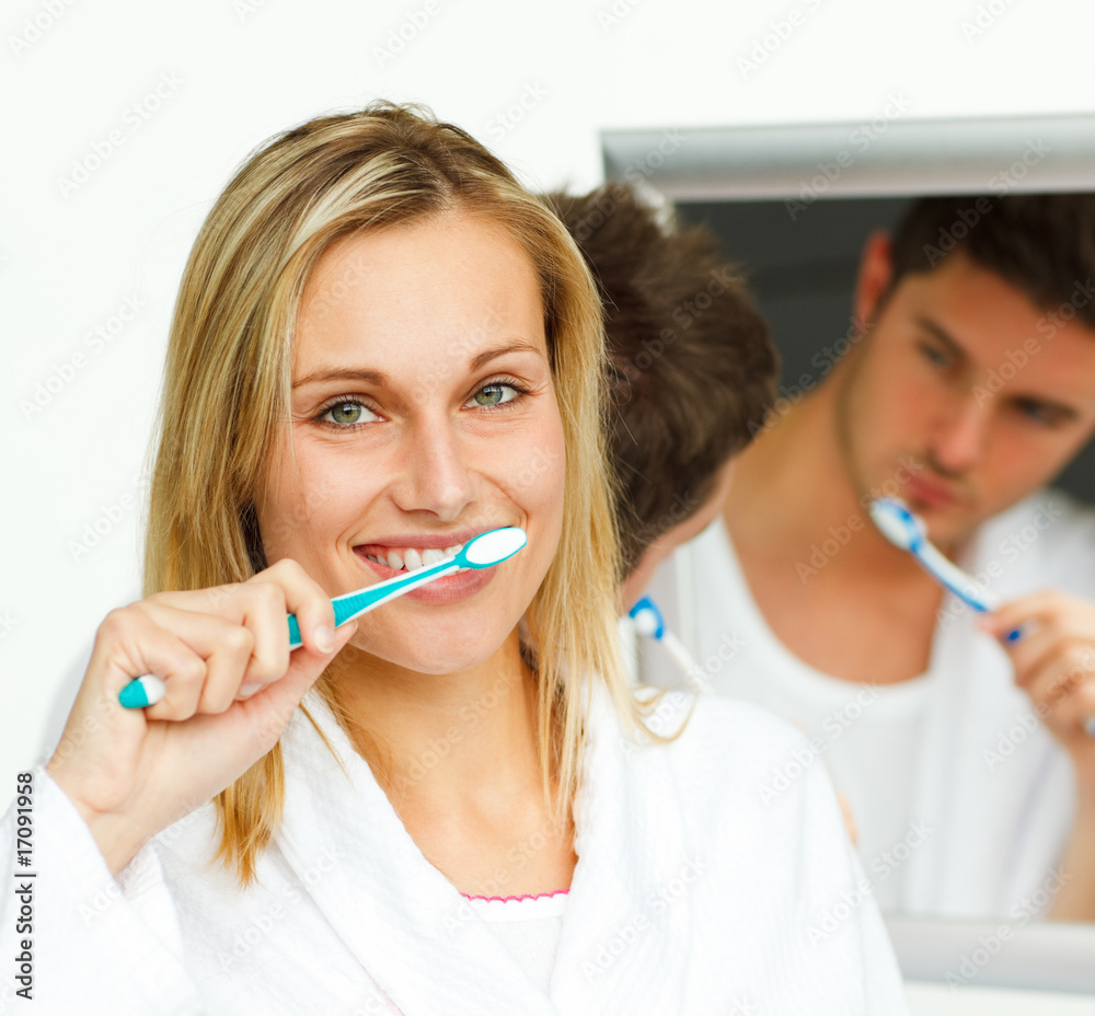 Portrait of an attractive woman cleaning her teeth with her boyf Portrait of an attractive woman cleaning her teeth with her boyf