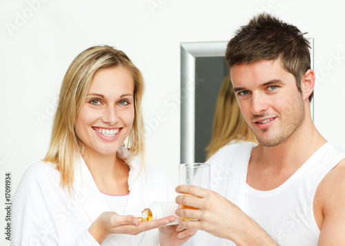 Woman holding pills and man with a glass of orange juice
