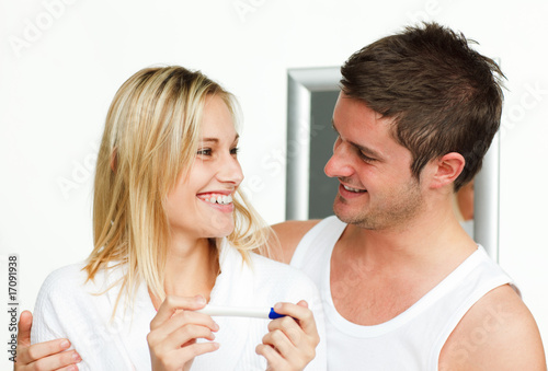 Happy couple holding a pregnancy test looking each other
