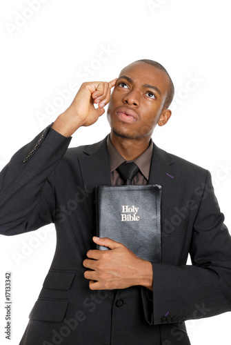 Man holding a bible whilst thinking