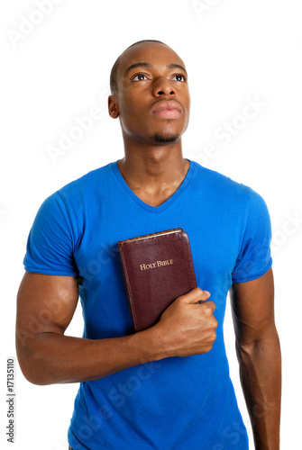 Student holding a bible looking up