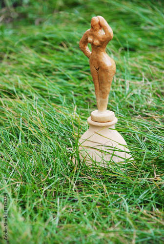 Primitive clay women figure in grass