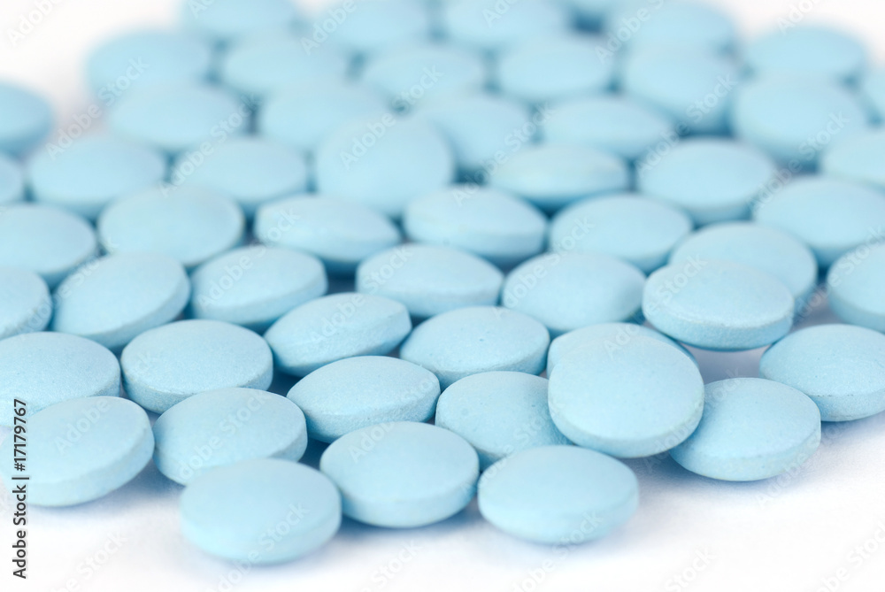 Blue pills on white with a shallow depth of field