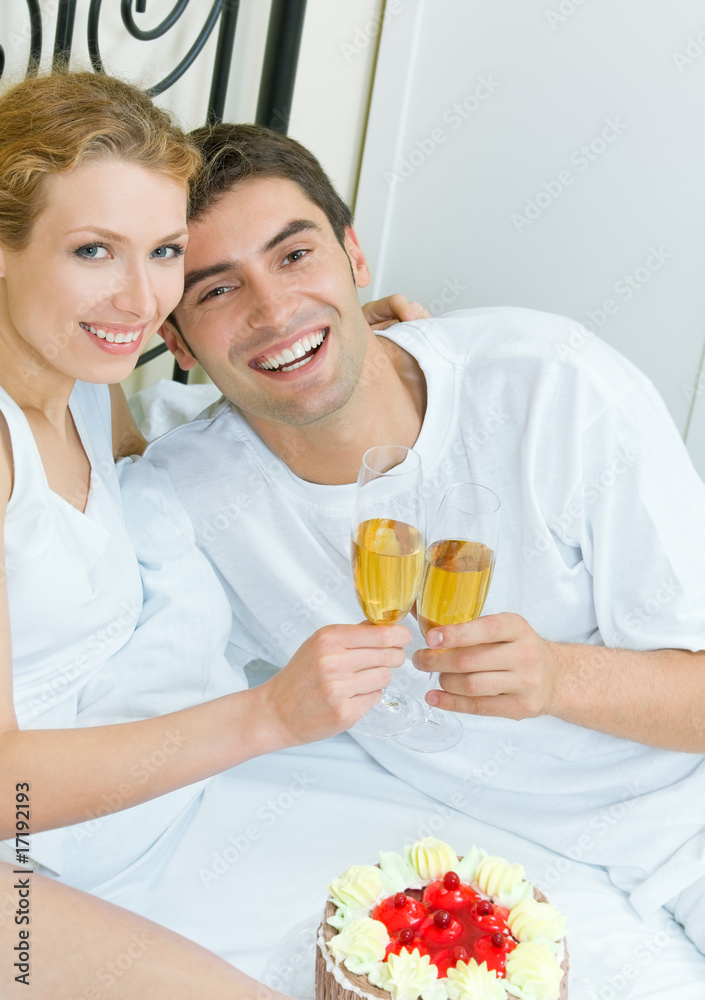 Young couple celebrating with champagne at bedroom