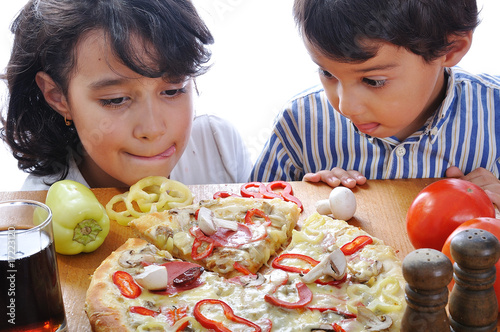 Two children with surprised face on pizza table photo