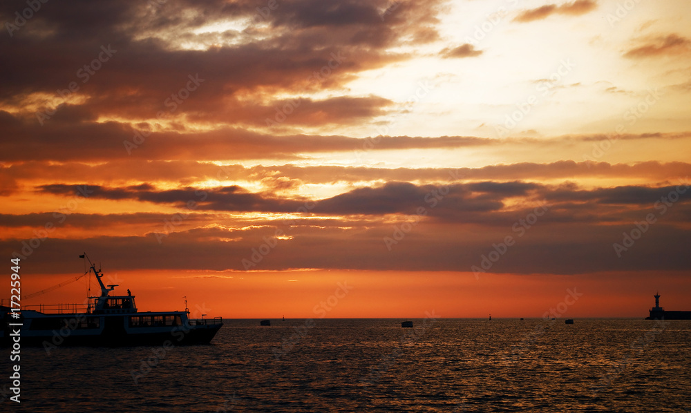 Yacht on horizon with golden orange clouds