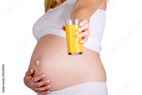 Presenting glass of orange juice in front of pregnant belly photo