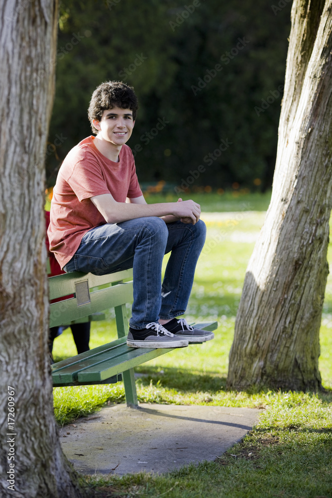 Naklejka premium Smiling Teenage Boy Sitting on Bench