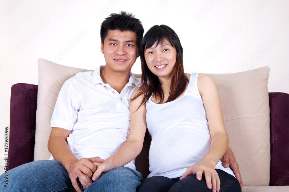 Husband and 8 months pregnant wife sitting on sofa. Husband and 8 months pregnant wife sitting on sofa.