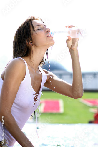 Attractive girl drinking water in city fountain