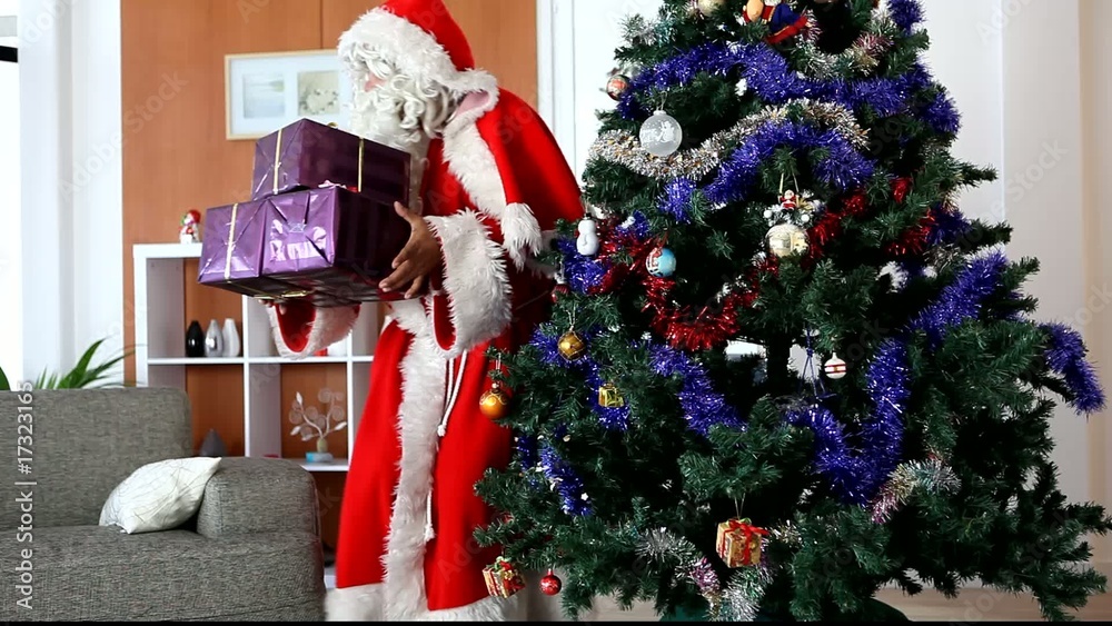 Père Noël deposant des cadeaux au pied d'un sapin