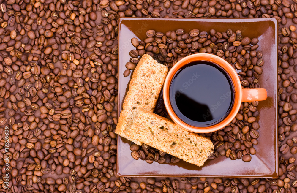 Naklejka premium Cup of black coffee with beans and rusks viewed from the top