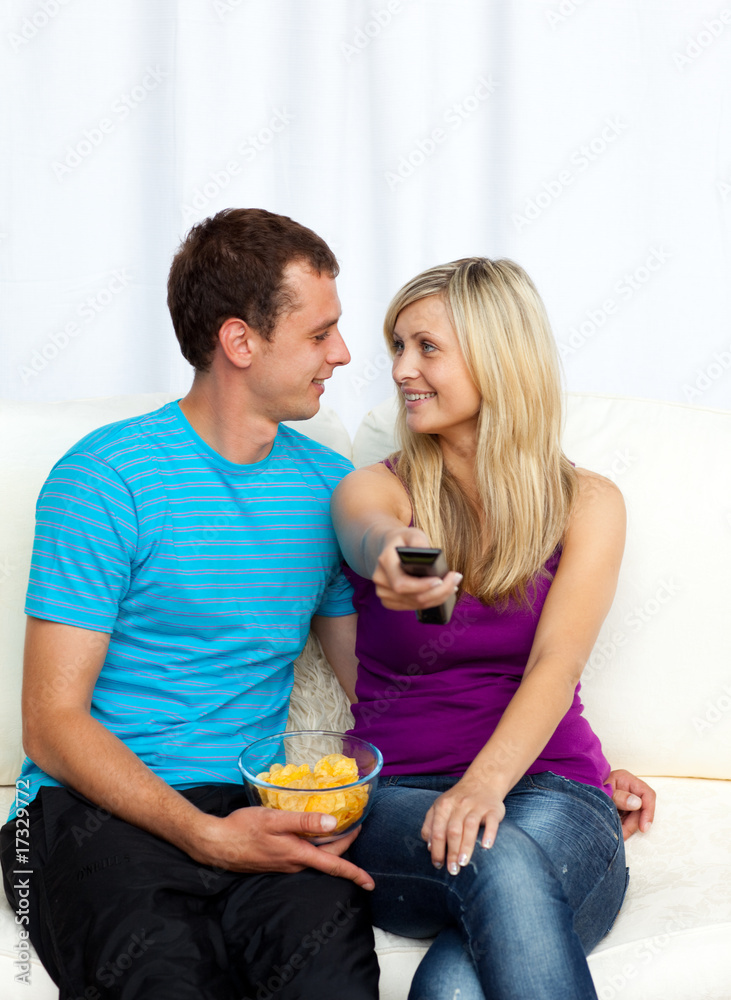 Lovers watching television and eating crisps