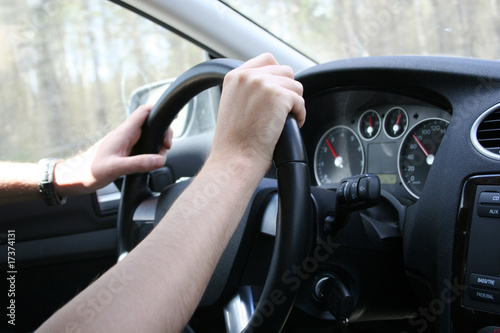 Driver man holds a steering wheel of his car