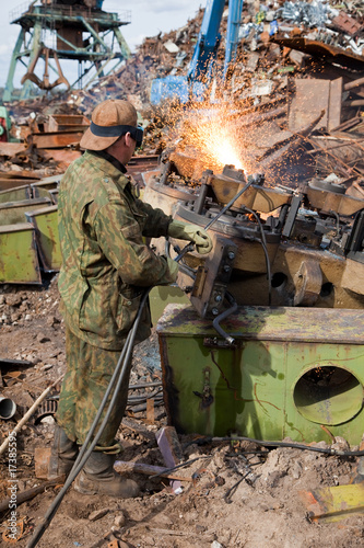 Welder using an acetylene torch to cut through a metal