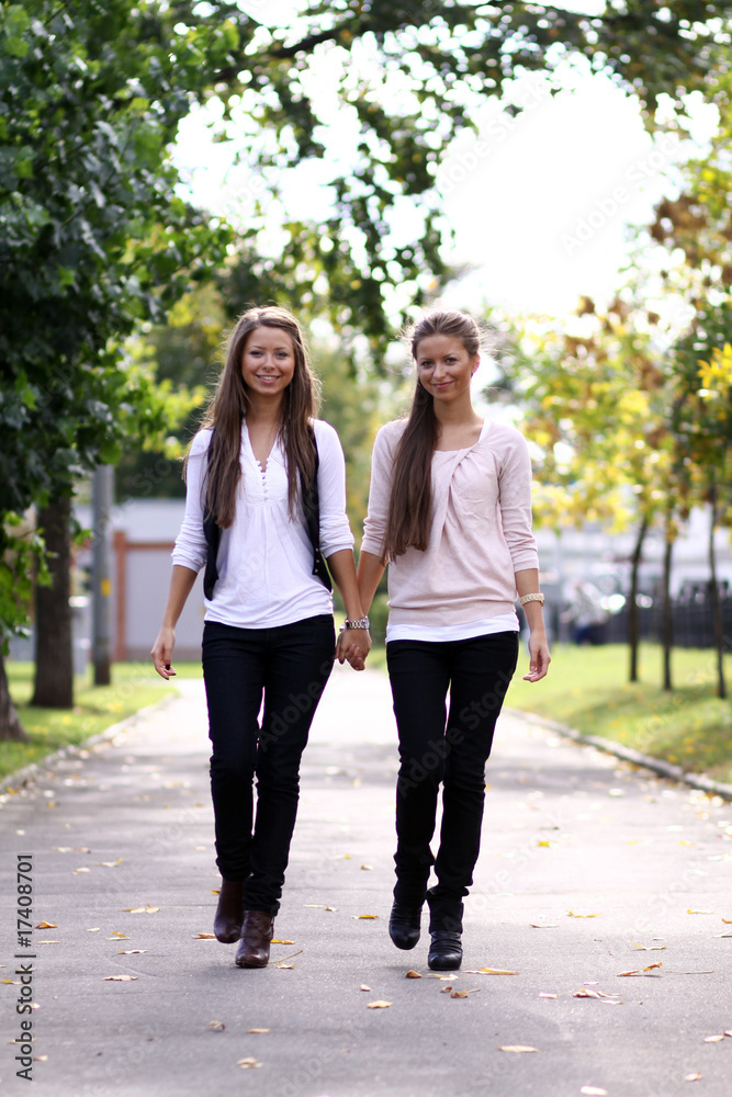 Obraz premium Fashionable girls twins walk in the street
