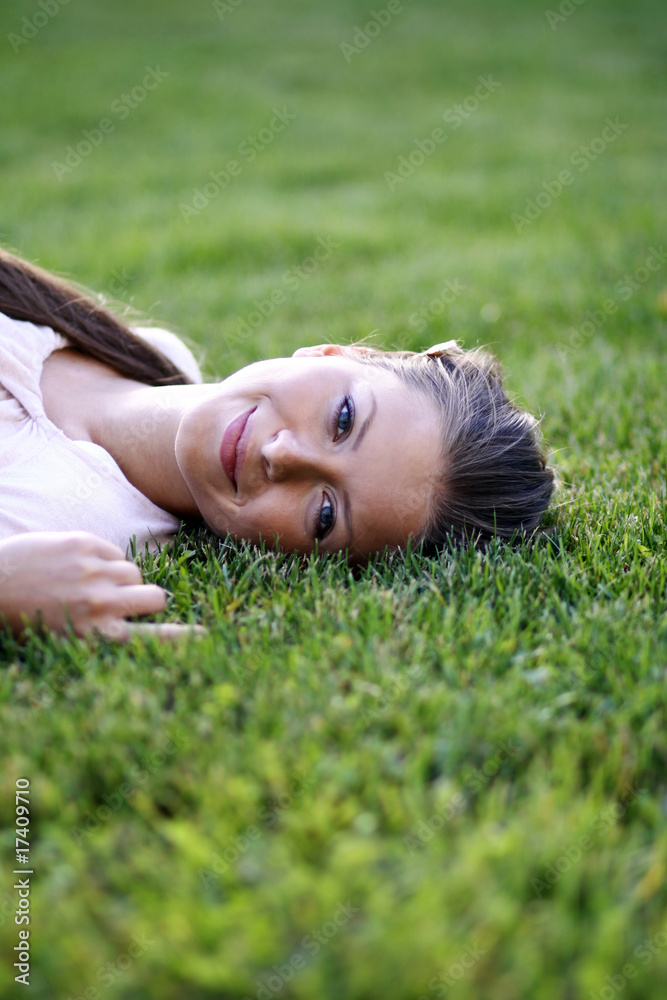 Cute young female lying on grass field at the park . Cute young female lying on grass field at the park .