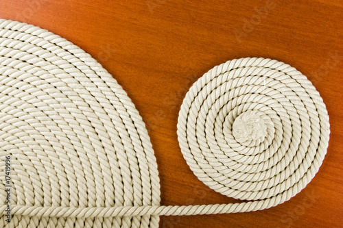Heavy, white coiled rope on wooden background.