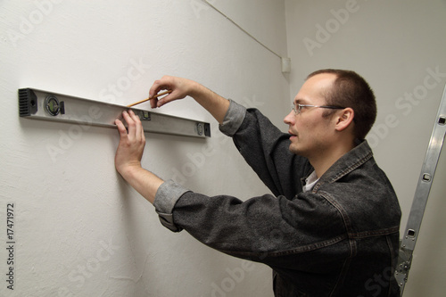 Man working level. Master measures the wall.