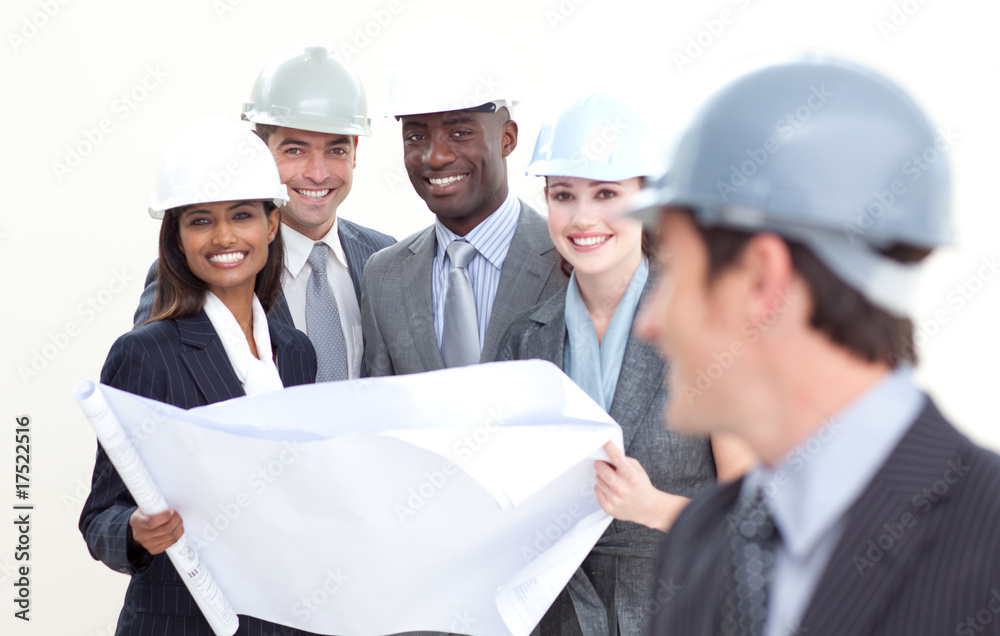 Engineer smiling at his team in the background Engineer smiling at his team in the background