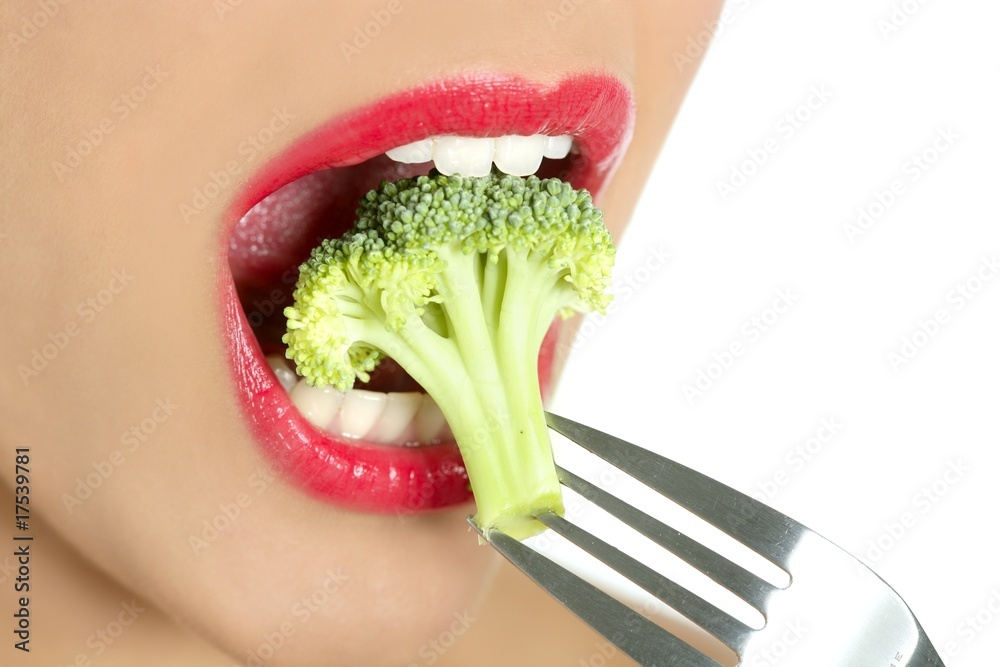 Fototapeta premium Broccoli on steel fork in woman mouth