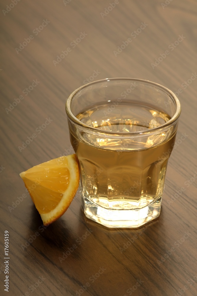 Tequila shot with lemon on a wooden table Tequila shot with lemon on a wooden table