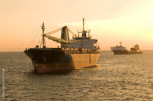 Colorful sky and dramatic sun with a ship silhouette on horizon