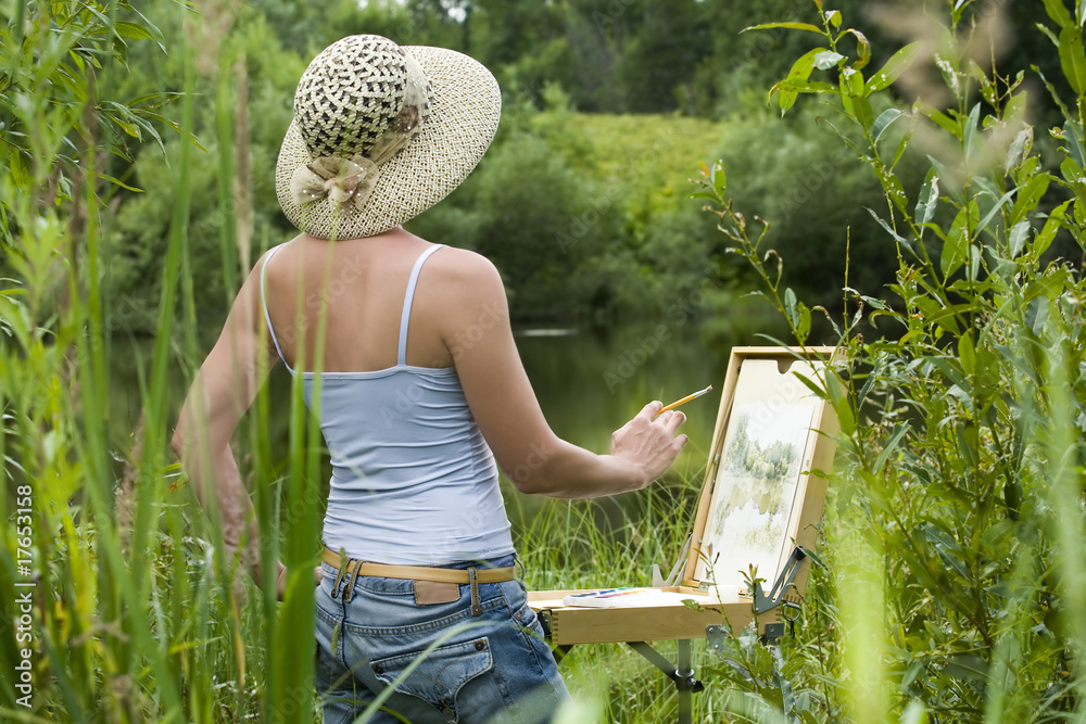 Fototapeta premium Young woman painting landscape in the open air