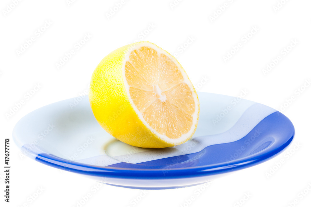 Ripe yellow lemon on dark blue saucer Ripe yellow lemon on dark blue saucer