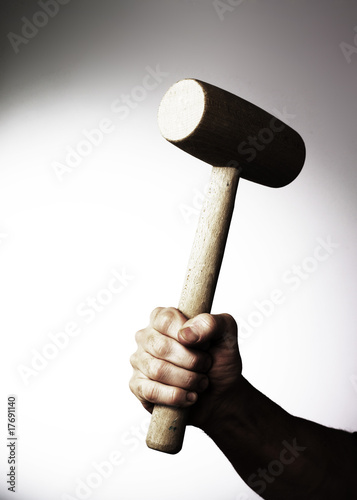 main tenant un marteau maillet bois levé