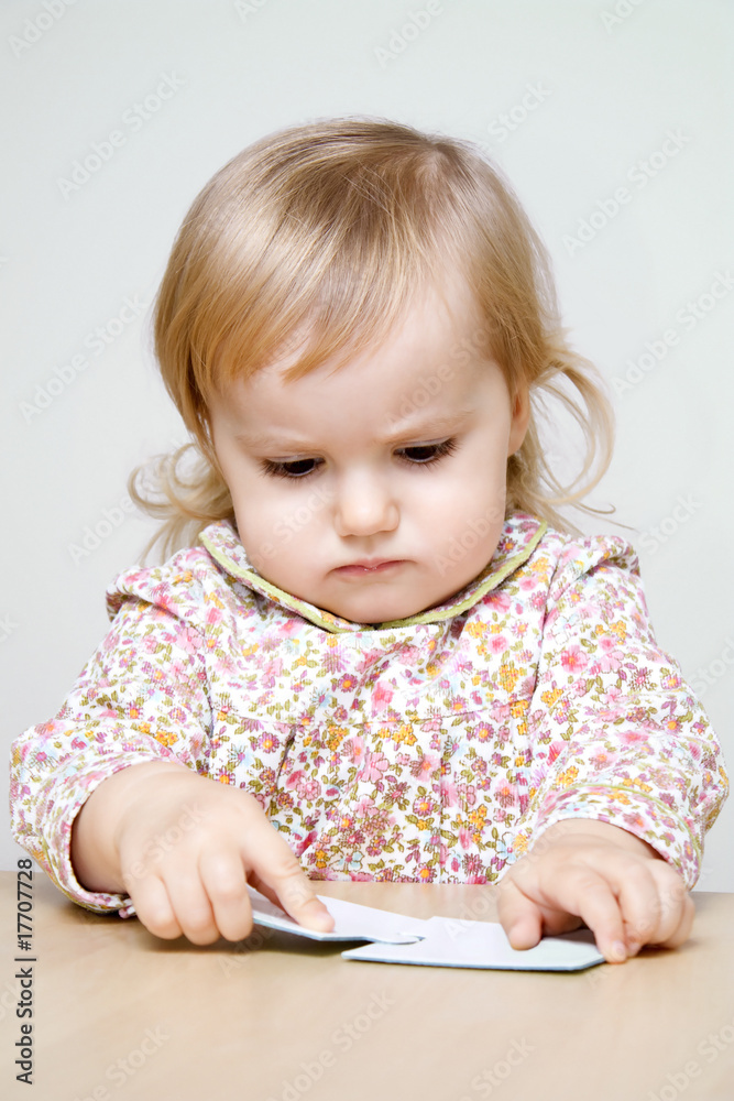 Serious little girl joining two puzzle pieces Serious little girl joining two puzzle pieces