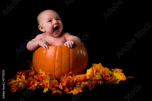 Baby in Large Pumpkin Isolated on Black