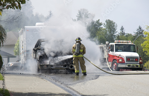 Fireman extinguishing burning vehicle