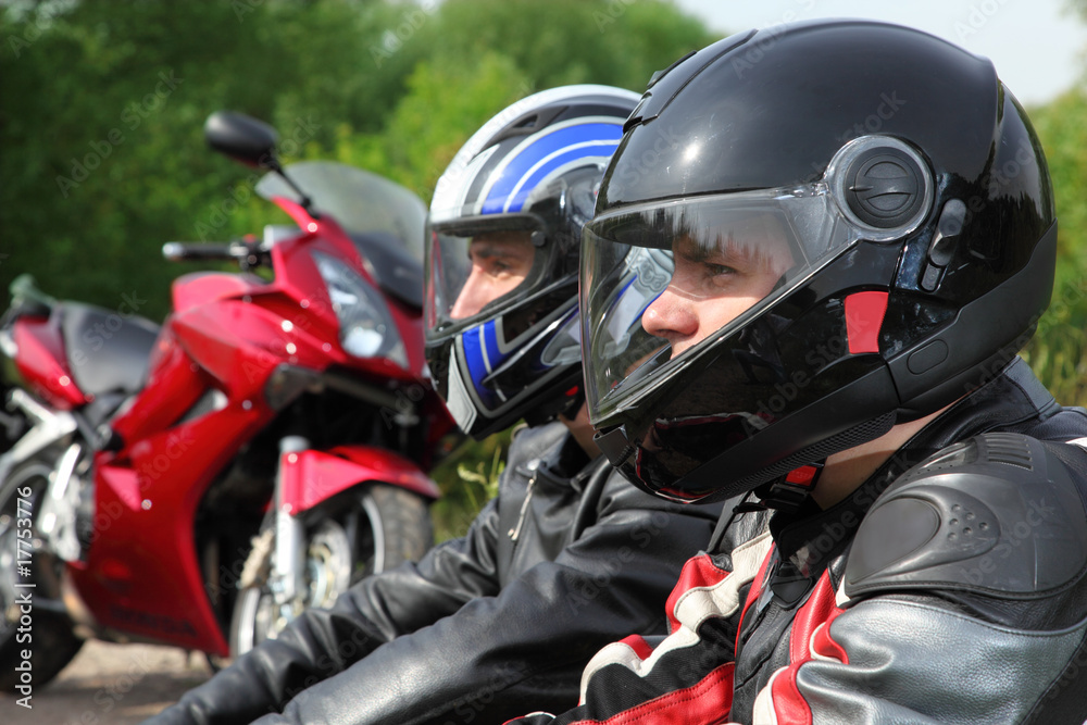 closeup of two motorcyclists sitting on country road near bikes closeup of two motorcyclists sitting on country road near bikes