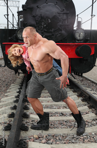 strong shirtless man saving little girl on railroad