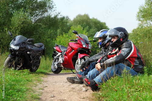 Obraz na plátně two motorcyclists sitting on country road near bikes