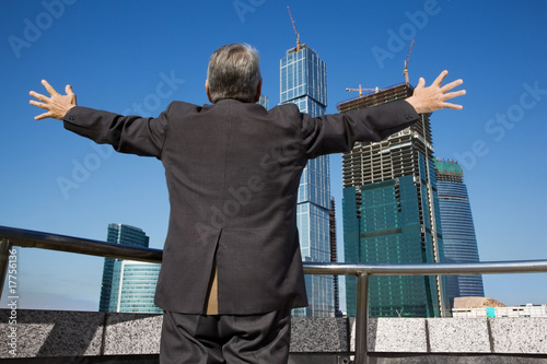 behind Senior man at the building with hand up