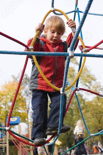 boy on playground climbing net of ropes