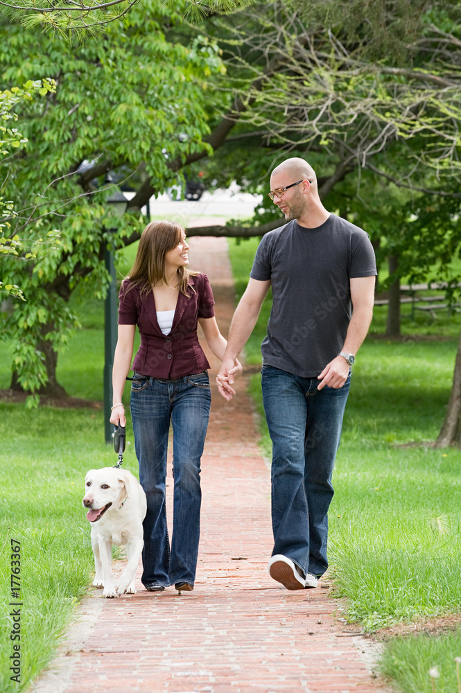Obraz premium Happy Young Couple Walking the Dog
