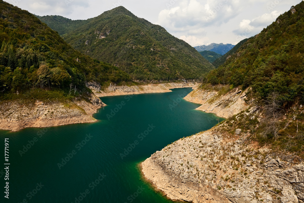 An artificial lake in mountains with low water level.