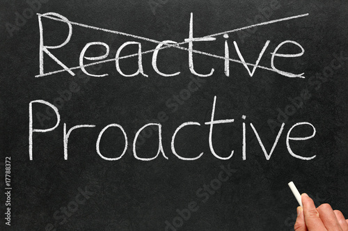 Fotografia Crossing out reactive and writing proactive on a blackboard.