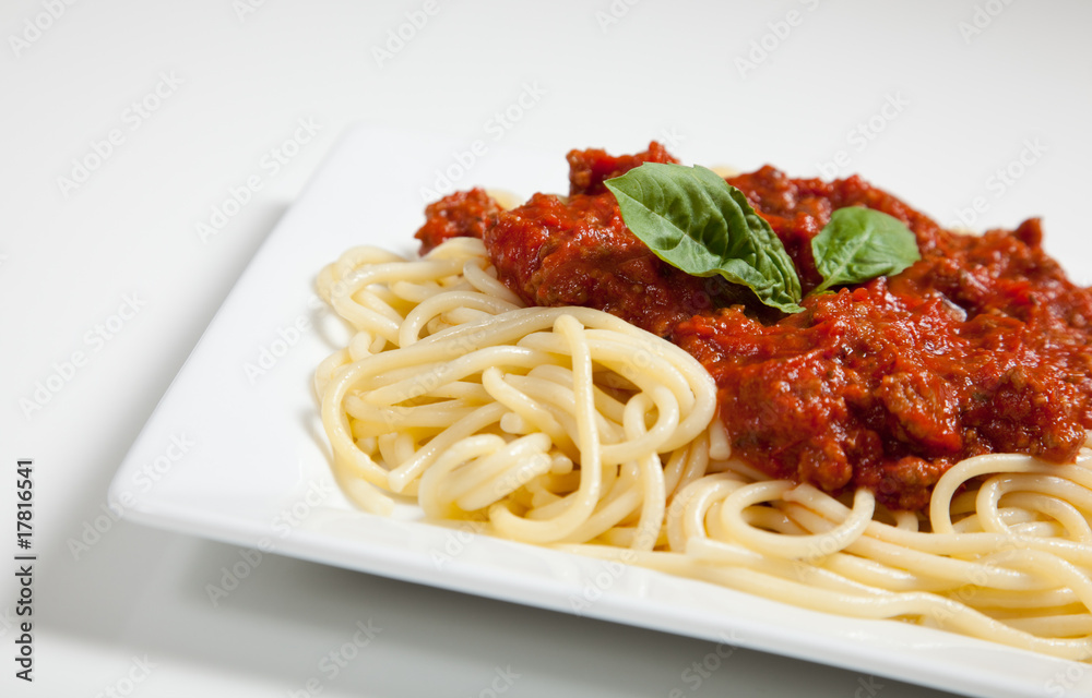 White plate of spaghetti and meat sauce with basil White plate of spaghetti and meat sauce with basil
